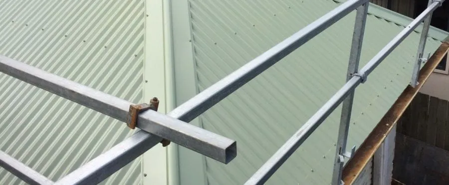 Metal roof sheeting being installed with safety rails set up around the edge